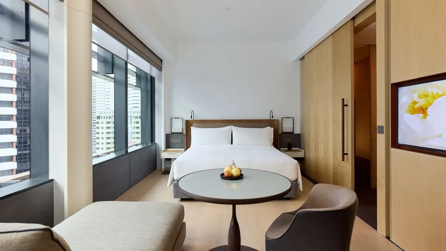 Bright Emerald Room at COMO Metropolitan Singapore with tall windows, city views and a round table
